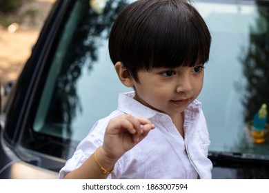 Indian Cute Boy Sitting On Car Bonnet