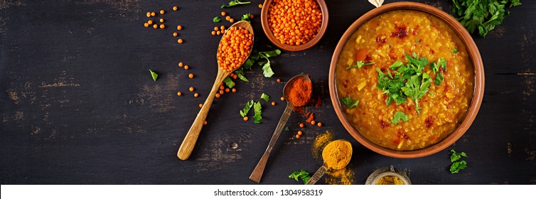 Indian Dal. Food. Traditional Indian Soup Lentils.  Indian Dhal Spicy Curry In Bowl, Spices, Herbs, Rustic Black Wooden Background. Top View. Authentic Indian Dish. Overhead. Banner