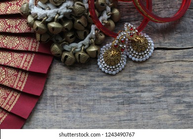 Indian decorations for dancing: bracelets, bells for the legs - ganguru, earrings and elements of the Indian classical costume for dancing bharatanatyam. Wooden background. Top view. Place for text.