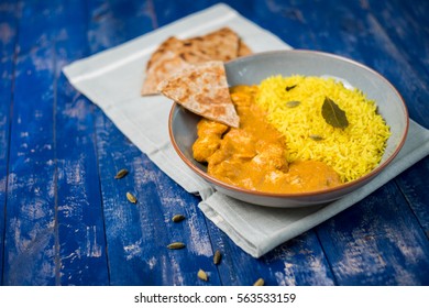An indian dish on a wooden table, chicken korma and flat bread