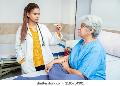 Indian Doctor Check Fever Of Old Senior Female Patient Using Thermometer At Hospital Or Clinic. Elderly People Health Care Concept.