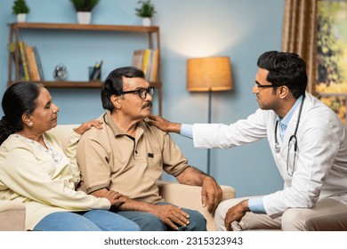 Indian doctor consoling senior couple by giving confidence while sitting on sofa at home - concept of mental illness, health care support and assistance - Powered by Shutterstock