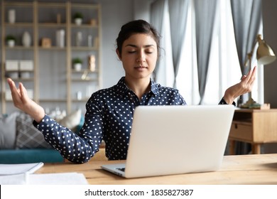 Indian Employee Sit At Workplace Desk Relaxing Do Yoga Asana Practice With Eyes Closed Folded Fingers Makes Mudra Gesture. No Psychological Stress At Workday, Fatigue Relief, Healthy Lifestyle Concept