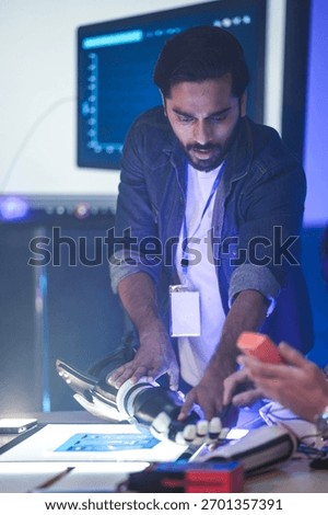 An Indian engineer in an RD lab tests an AI-powered prosthetic arm. The bionic hand has glowing fingertips, showing its advanced sensor technology or system activation.