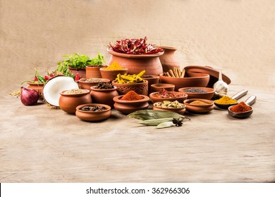 Indian essential spices in terracotta pots arranged over textured background, selective focus