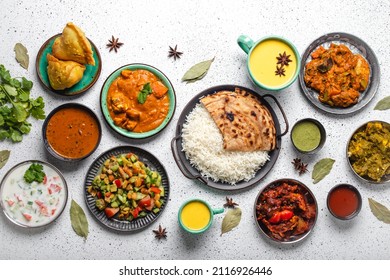 Indian Ethnic Food Buffet On White Concrete Table From Above: Curry, Samosa, Rice Biryani, Dal, Paneer, Chapatti, Naan, Chicken Tikka Masala, Mango Lassi, Dishes Of India For Dinner Background