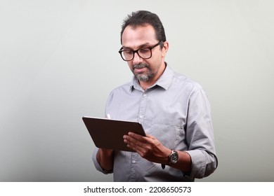 Indian ethnic middle aged man working on his tablet phone