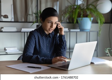 Indian ethnicity businesswoman search on laptop information while talking with client on phone. Manager agent solve help to company customer distantly, modern tech usage, busy fruitful workday concept - Powered by Shutterstock