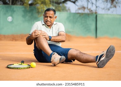 Indian fallen injured senior man suffering from knee pain while playing tennis at court - concept of emergency, painful and inflammation. - Powered by Shutterstock