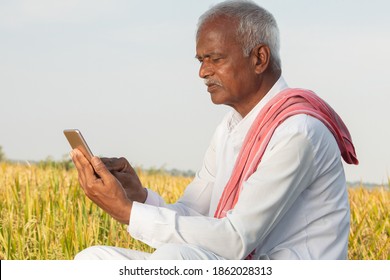 Indian Famer Using Mobile At Agricultural Farm Land - Elder Villager Using Phone - Concept Of Senior Rural People Using Technology And Smartphone