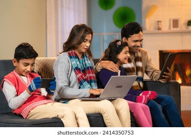 Indian family busy using digital devices at home during holidays - concept of technology addiction, internet connection and generation - Powered by Shutterstock