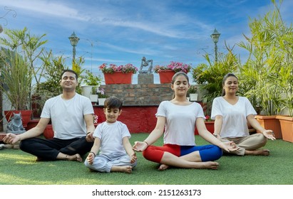 indian family doing yoga in garden  - Shutterstock ID 2151263173