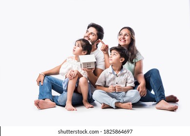 Indian Family Father, Mother, Son And Daughter Holding 3D Paper Model Of Home - Real Istate Concept In India