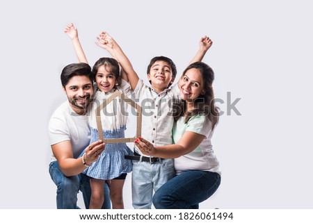 Indian family Father, mother, son and daughter holding 3D paper model of home - Real Istate Concept in India