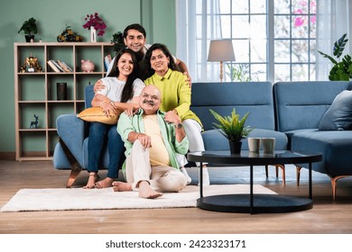 Indian family of four posing for a group photo in living room at modern home - Powered by Shutterstock