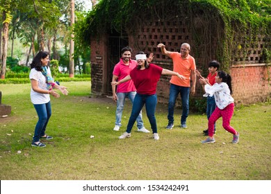 Indian Family Playing Blindfold Game In Park Or Garden, Multi Generation Asian Family Playing Outdoor Fun Games