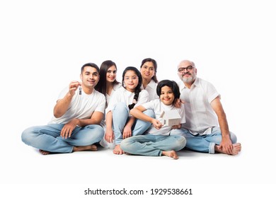 Indian Family And Real Estate Concept - Multigenerational Asian Family Holding Paper House Model With Keys Against White Background