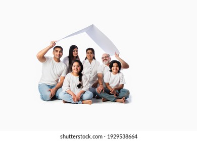 Indian Family And Real Estate Concept - Multigenerational Asian Family Holding Paper House Model With Keys Against White Background