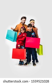 Indian Family With Shopping Bags In Winter Wear /warm Clothes Against Background