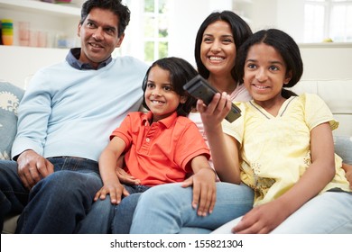 Indian Family Sitting On Sofa Watching TV Together