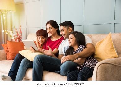 Indian family sitting on sofa and using smartphone, laptop or tablet, watching movie or surfing internet - Shutterstock ID 1833733024