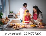 an Indian family standing in the kitchen They help each other prepare the food that they ordered. Arrange in a container placed on the table, to family and Indian food concept.