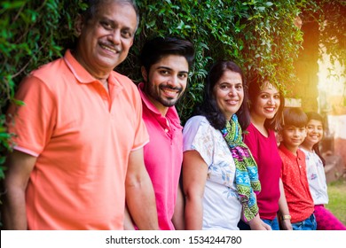 Indian Family Standing In Line Against Wall Covered With Creepers. Multi Generation Of Asian Family In Park Or Garden Having Fun, Healthy Family Life Concept