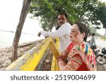 An Indian Family standing near the railing guard of nauka vihar taal lake of Gorakhpur under cloudy weather