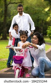 Indian Family Teaching Their Kids Cycling In The Outdoor Park