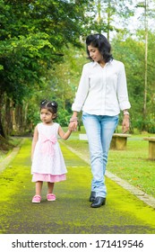 Indian Family Walking On Garden Path. Mother And Daughter Holding Hands At Outdoor Park.