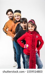 Indian Family In Warm Clothes Standing Against White Background. Ready For Winter