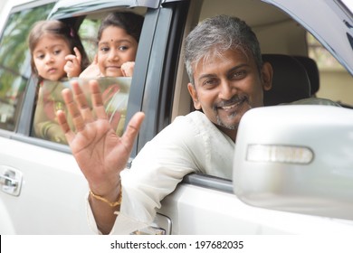 Indian Family Waving Hands And Saying Goodbye, Sitting In Car Ready To Trip. Asian Family Lifestyle.