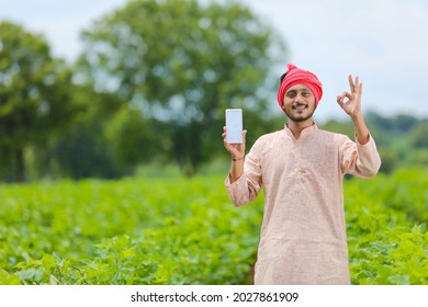 Indian farmer showing smartphone screen at agriculture field. - Powered by Shutterstock