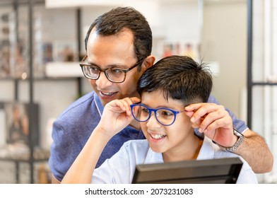 Indian father and son choosing eyeglasses in optics store