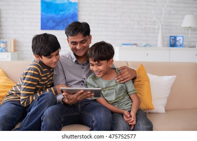 Indian Father And Sons Watching Movie On Tablet Computer