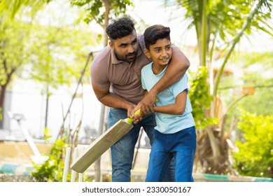 indian father teaching his son to playing cricket game at park - concept of Shared passion, family bonding and fatherhood - Powered by Shutterstock