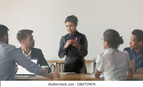 Indian Female Coach Stand Holding Meeting With Diverse Work Team Discussing Sharing Ideas In Conference Room, Multiethnic People Or Colleague Brainstorm Talking Cooperating At Office Briefing