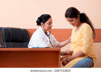 indian female doctor checking up to pregnant lady at clinic - Powered by Shutterstock