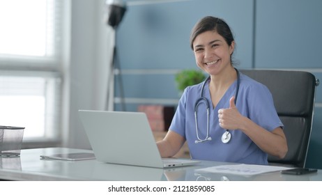 Indian Female Doctor Showing Thumbs Up Sign While using Laptop in Office - Powered by Shutterstock