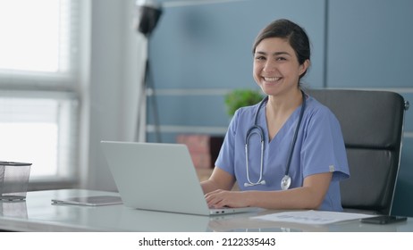 Indian Female Doctor Smiling At Camera While Using Laptop In Office