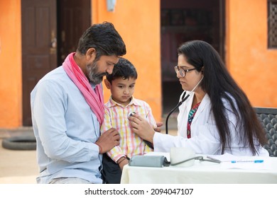 Indian female doctor with stethoscope checking little child patient heart beat or breath at village, Kid with his father getting examine by medical person, Rural India healthcare concept