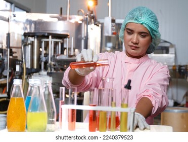 Indian female food engineer test tubes to sample beverage products in a juice beverage factory. Food and beverage quality and safety testing concepts Factory product production process - Powered by Shutterstock