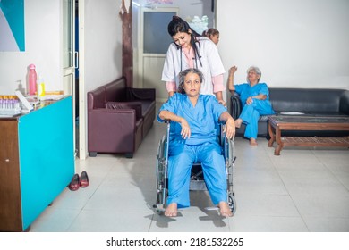 Indian Female Nurse Or Medical Staff Helping Disabled Elderly Woman Patient In Wheelchair At Hospital, Doctor With Old Lady, Healthcare Concept.