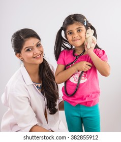 Indian Female Paediatric Doctor Playing With A Cute Baby Girl Patient, Isolated Over White Background