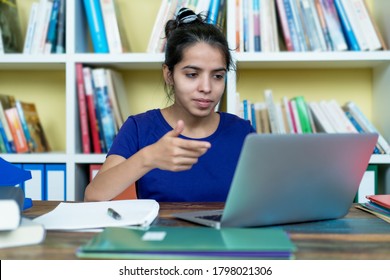 Indian female student talking with other students after online lecture at home at desk