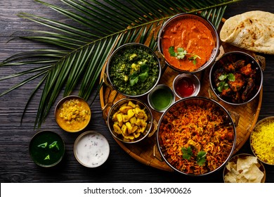 Indian Food Curry Butter Chicken, Palak Paneer, Chiken Tikka, Biryani, Vegetable Curry, Papad, Dal, Palak Sabji, Jira Alu, Rice With Saffron On Dark Background