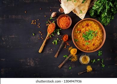 Indian food dal. Traditional Indian soup lentils.  Indian Dhal spicy curry in bowl, spices, herbs, rustic black wooden background. Top view.  Authentic Indian dish. Overhead. Flat lay