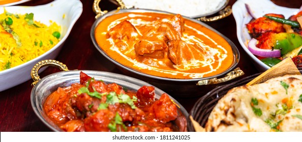 Indian Food On Dark Wooden Background. Dishes And Appetizers Of Indian Cuisine. Curry, Butter Chicken, Rice, Lentils, Paneer, Naan, Chutney, Spices. 