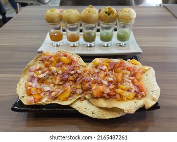 Indian Foods And Snacks Of Toasted Masala Papad (paper Thin Wheat Wafer) And Pani Puri Golden Balls With Spicy Sauces On A Table