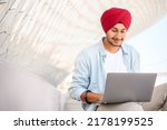 Indian freelancer man in traditional turban sitting outdoors with laptop, developer working on the distance, hindu guy enjoys remote work, male student studying online, e-learning concept